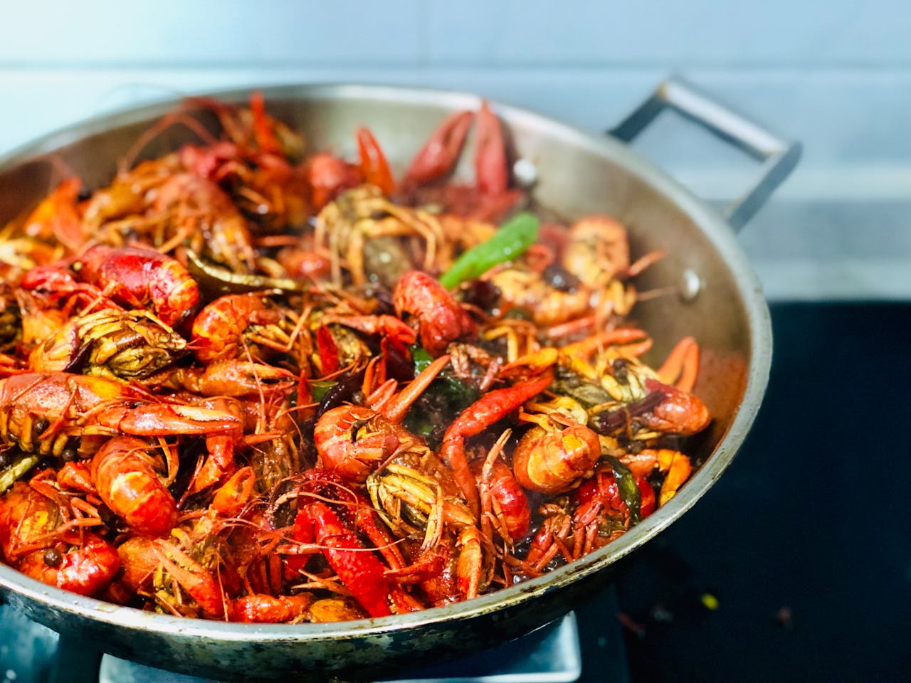 A sizzling pan filled with succulent crawfish and vibrant spices, showcasing a seafood feast.